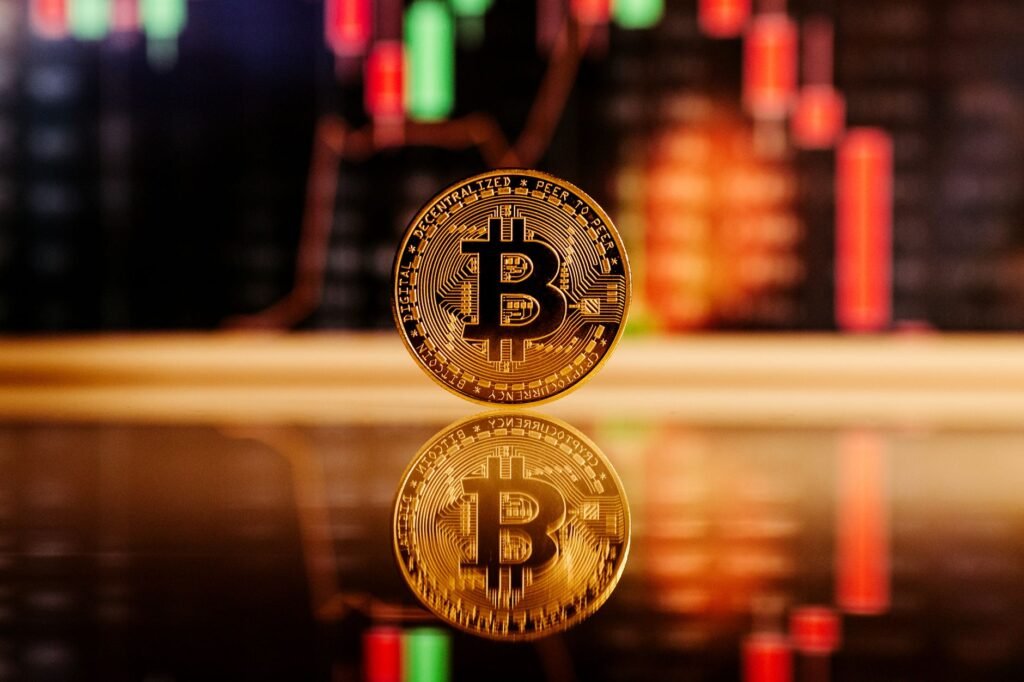 Close-up de uma moeda Bitcoin com um gráfico de mercado de ações ao fundo, simbolizando o comércio de criptomoedas.