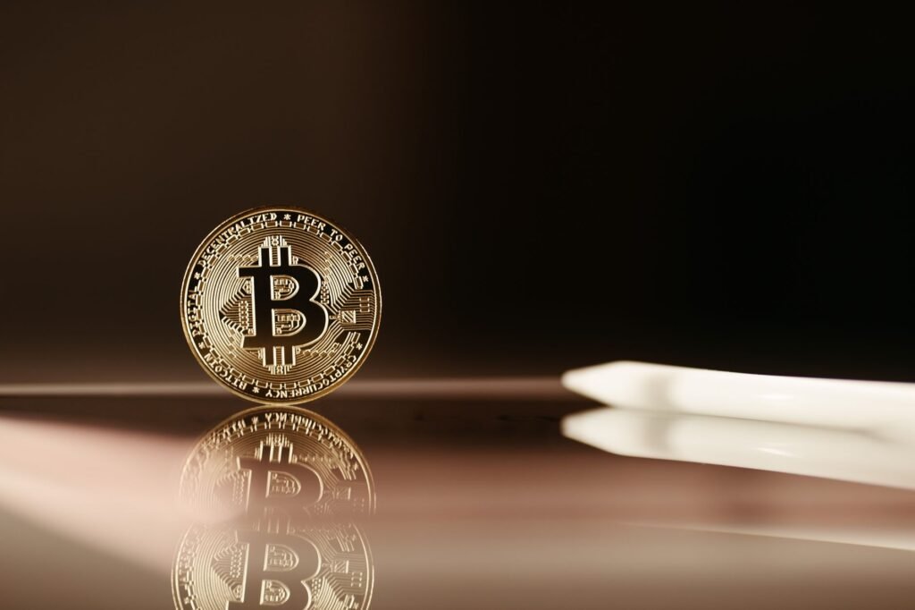 Uma imagem em close de uma moeda Bitcoin refletindo em uma superfície brilhante, destacando temas de criptomoeda.