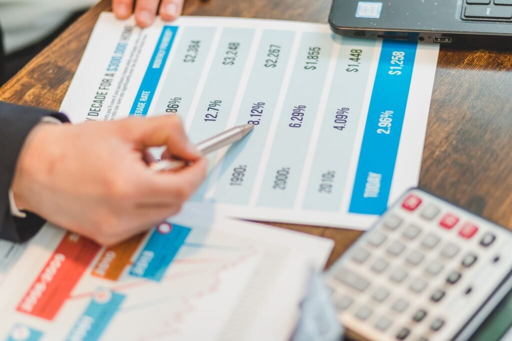 Close-up de documentos financeiros com gráficos e uma calculadora usada para análise de negócios.