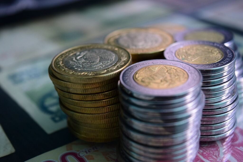 Close-up de pilhas de moedas de ouro e prata sobre diversas notas de moeda, simbolizando riqueza e economia.