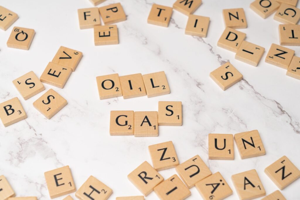 Peças de Scrabble sobre mármore soletrando 'óleo' e 'gás', conceito de energia e criatividade.