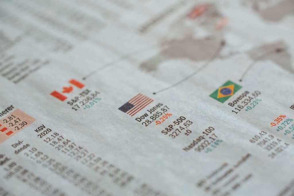 Close-up detalhado de um jornal exibindo estatísticas do mercado financeiro global e bandeiras de países.