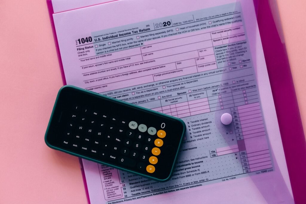 Formulário fiscal 1040 com uma calculadora em um fundo rosa, destacando temas de finanças e contabilidade.
